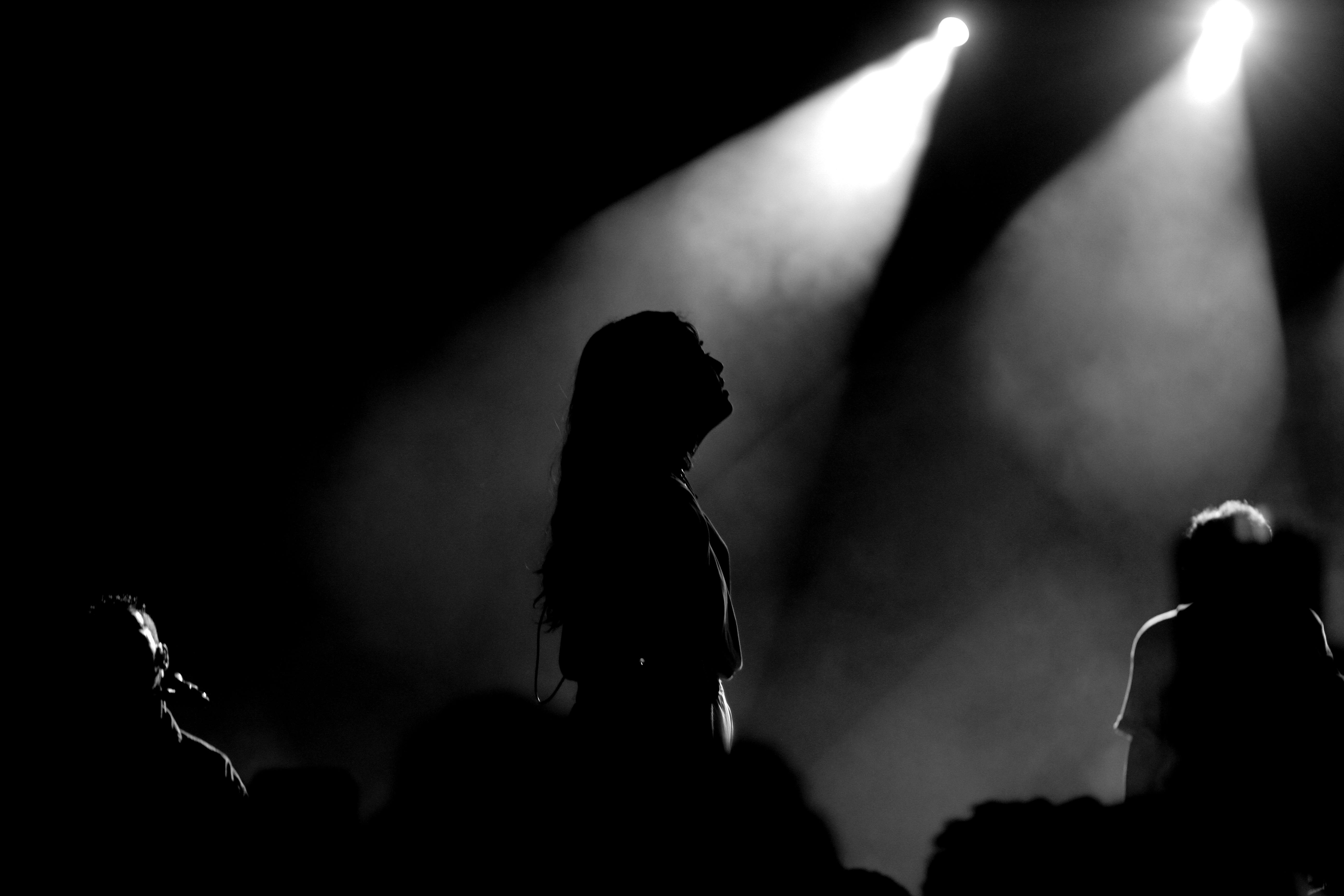 Free Silhouetted performers create a moody atmosphere under bright stage lights. Stock Photo