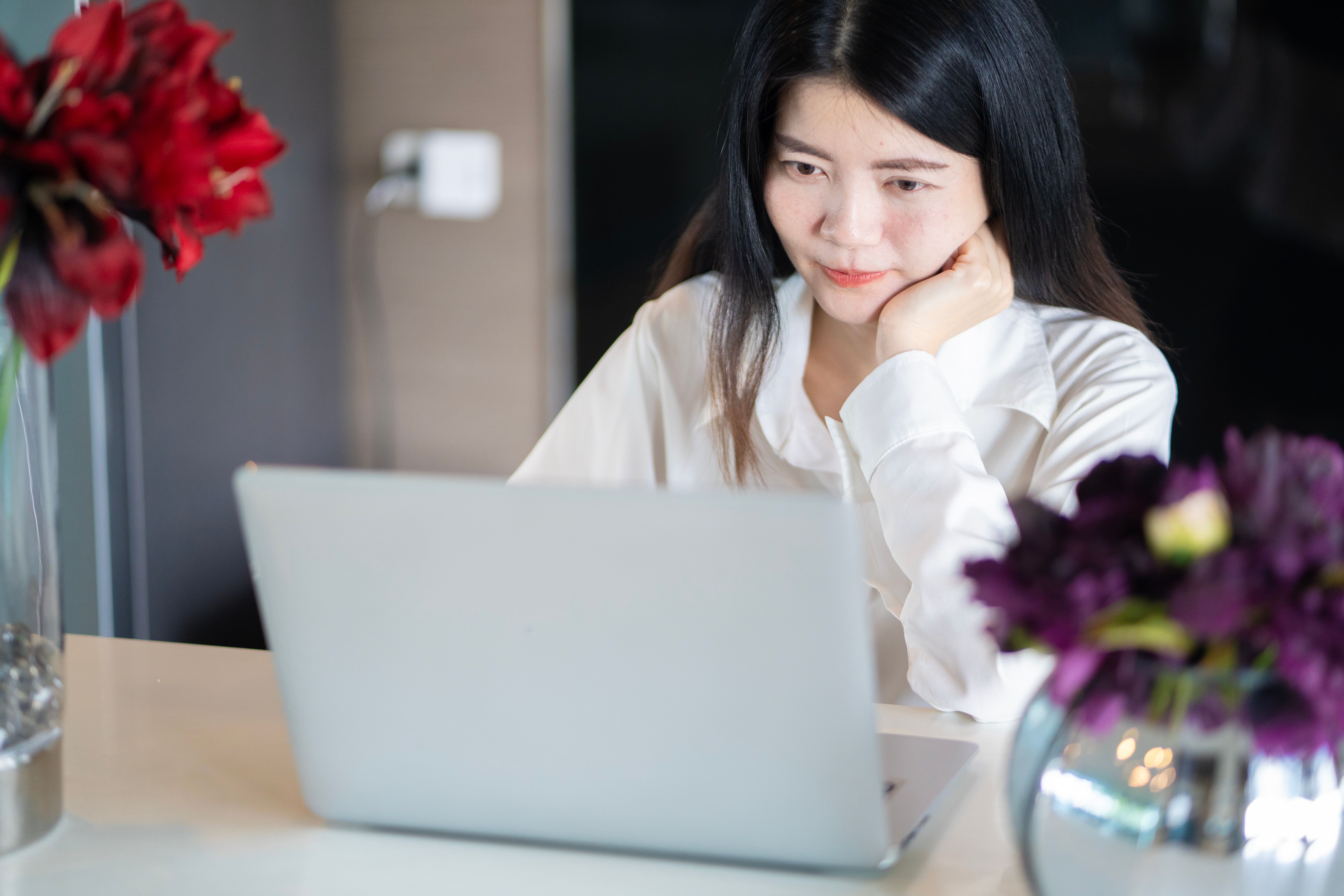 A professional planning next steps in a notebook beside a laptop
