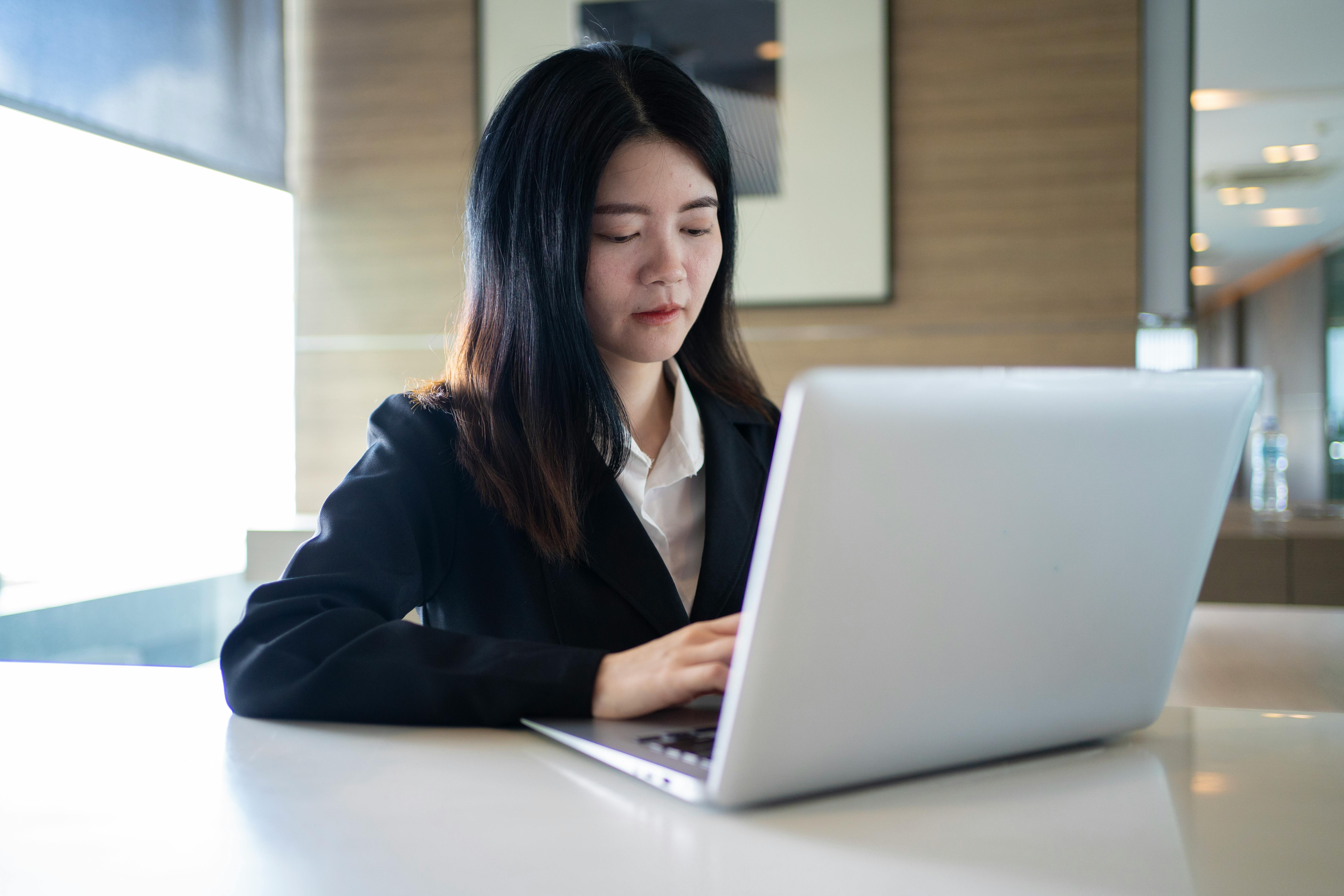 Confident young woman working on a laptop in a modern Bangkok office.