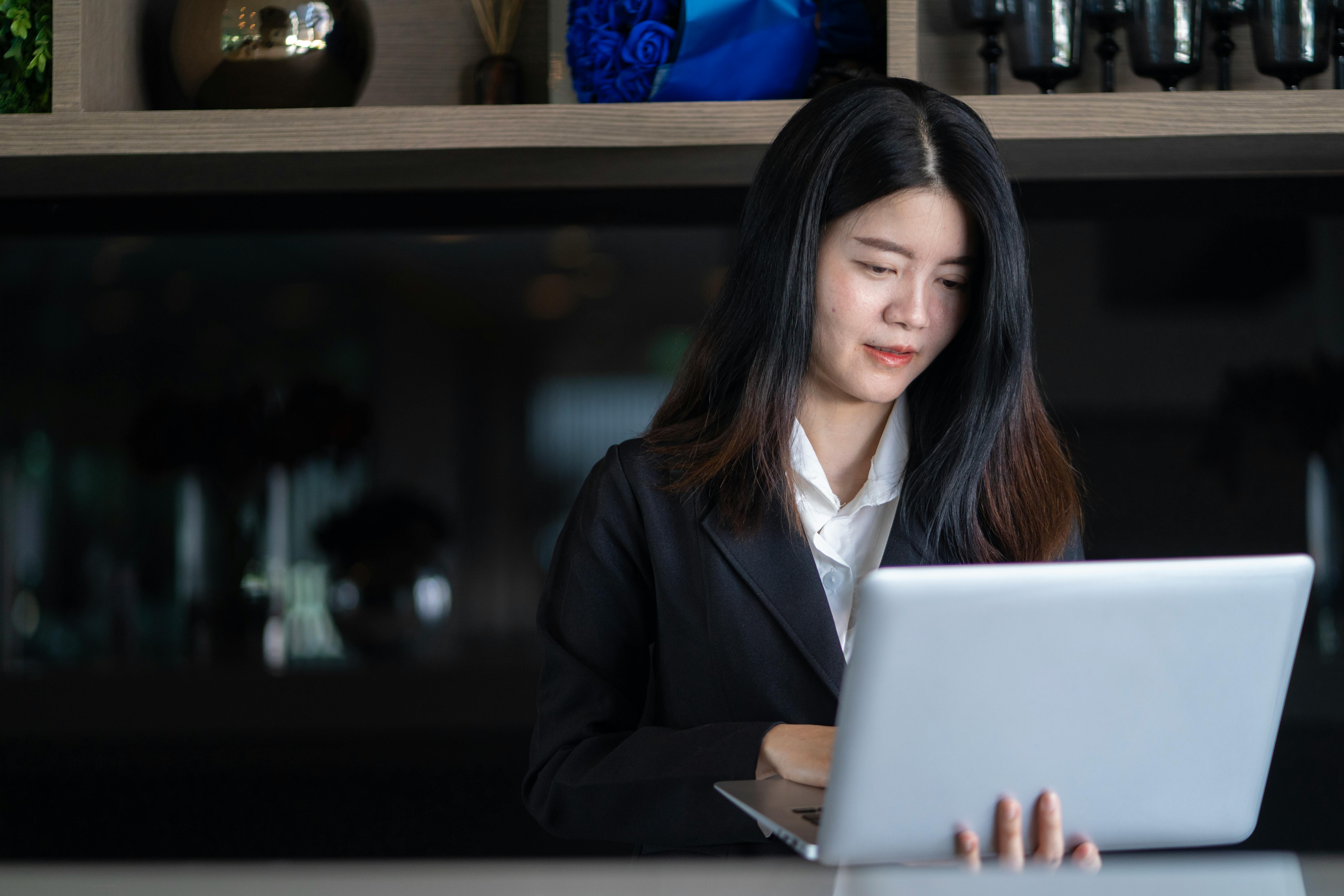Young Asian businesswoman in a modern office, focused on work with her laptop. Professional and successful.