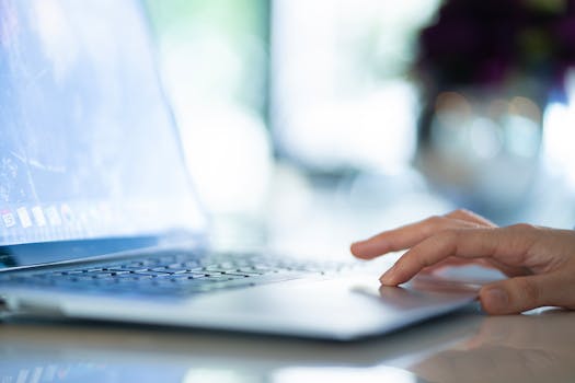 A hand navigates on a laptop in a bright modern office, conveying productivity.
