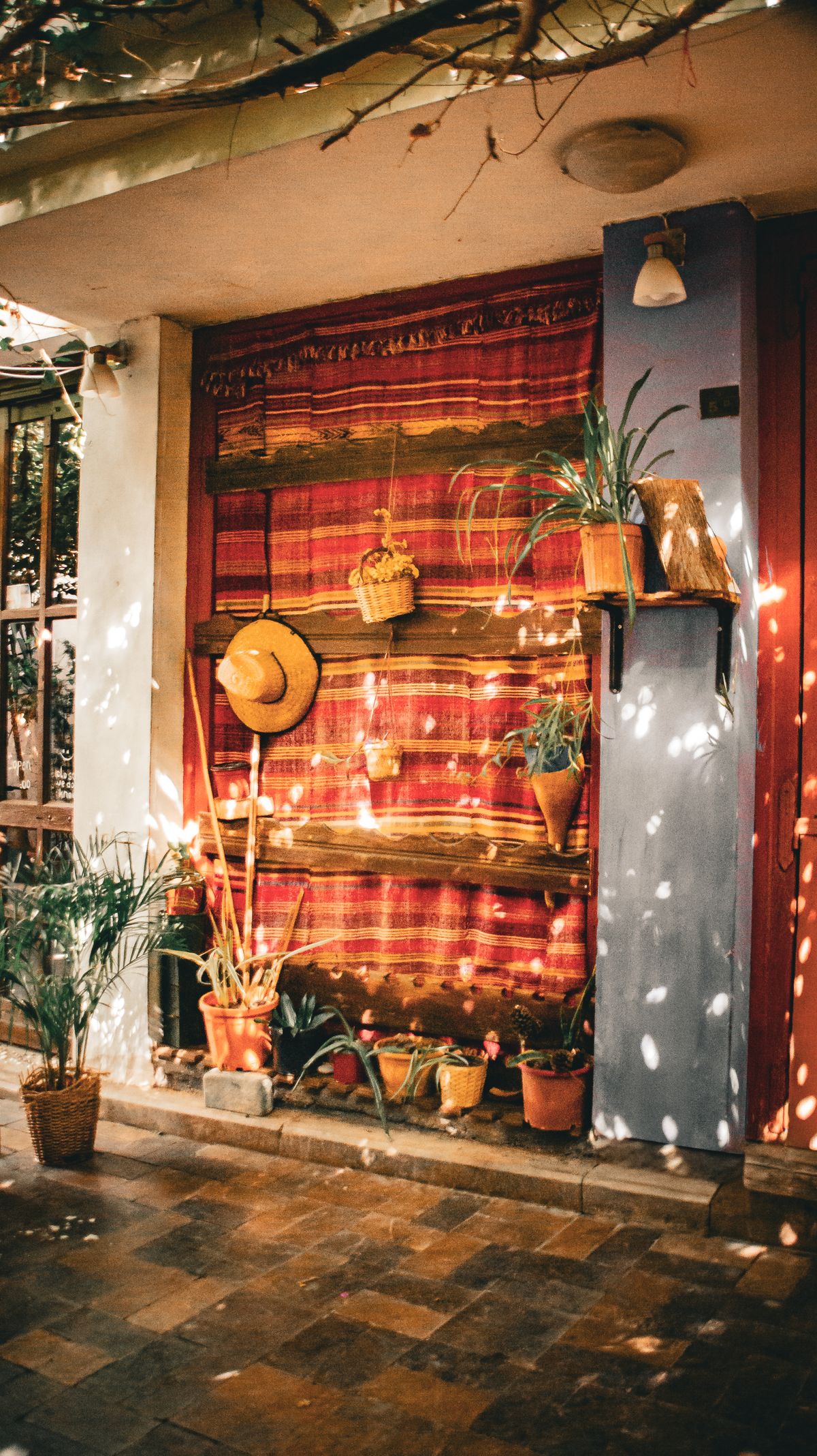 Cozy rustic outdoor patio featuring colorful textiles and vibrant potted plants. Stock Photo.