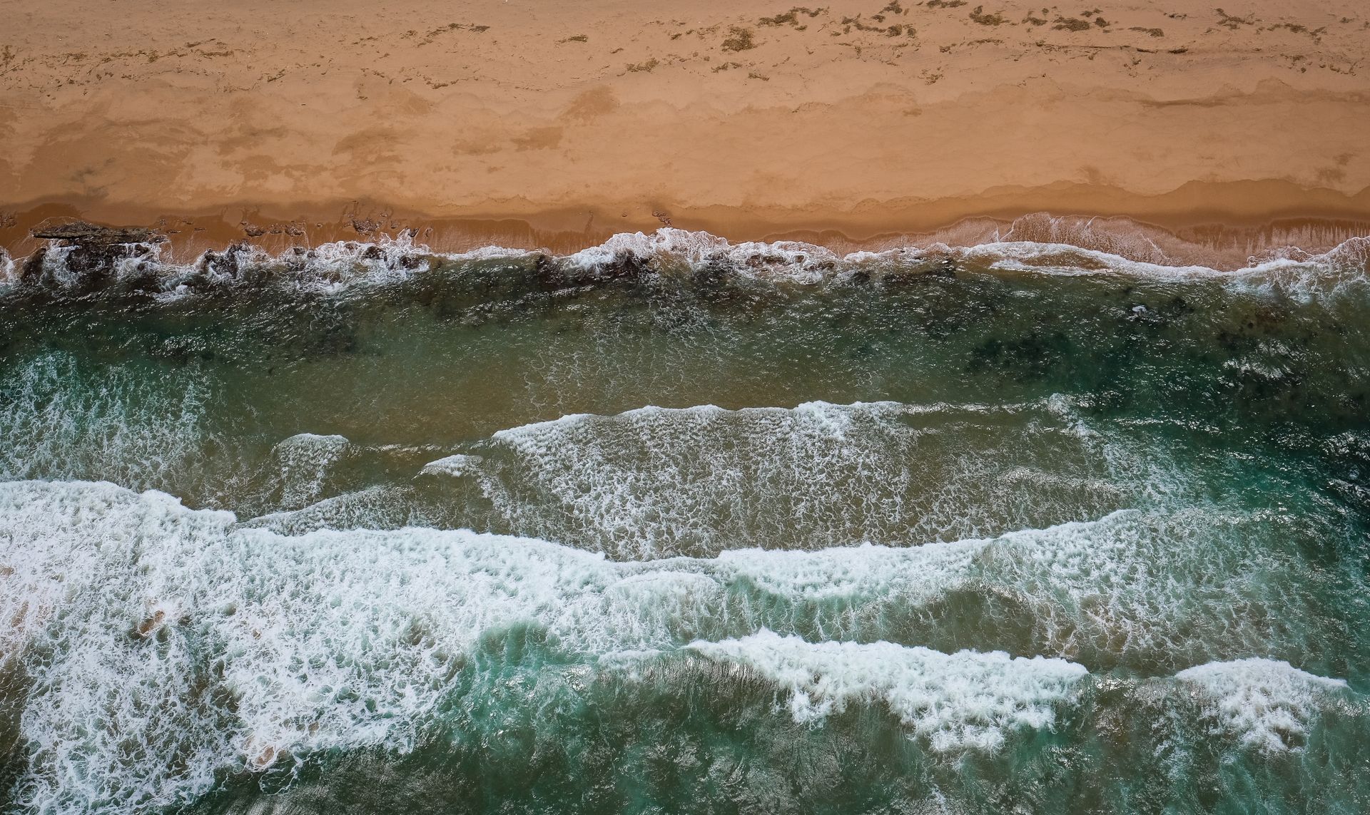 A stunning aerial view capturing waves crashing on the sandy shores of Dolphin Coast, South Africa.