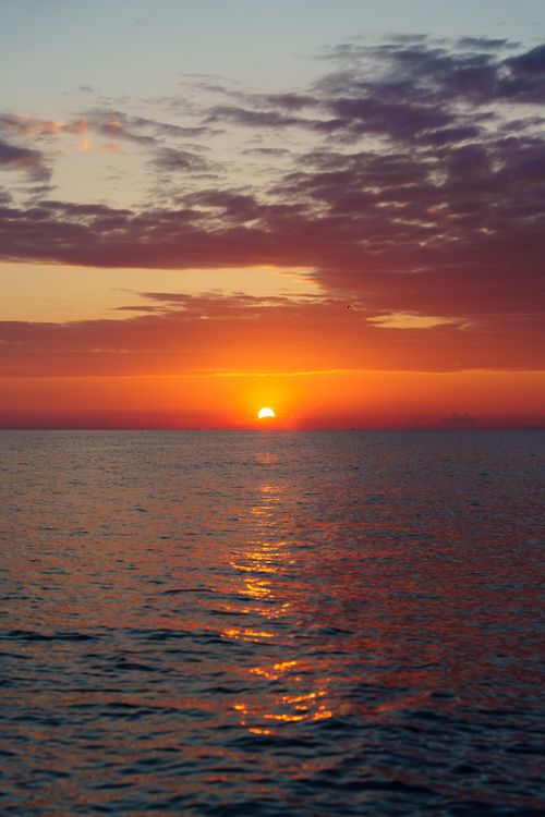 Free A breathtaking sunrise over a tranquil ocean with vivid colors and gentle waves. Stock Photo