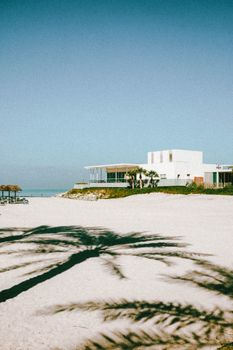 Scenic view of a beachfront resort in Ras Al Khaimah, UAE with palm shadows on the sand.