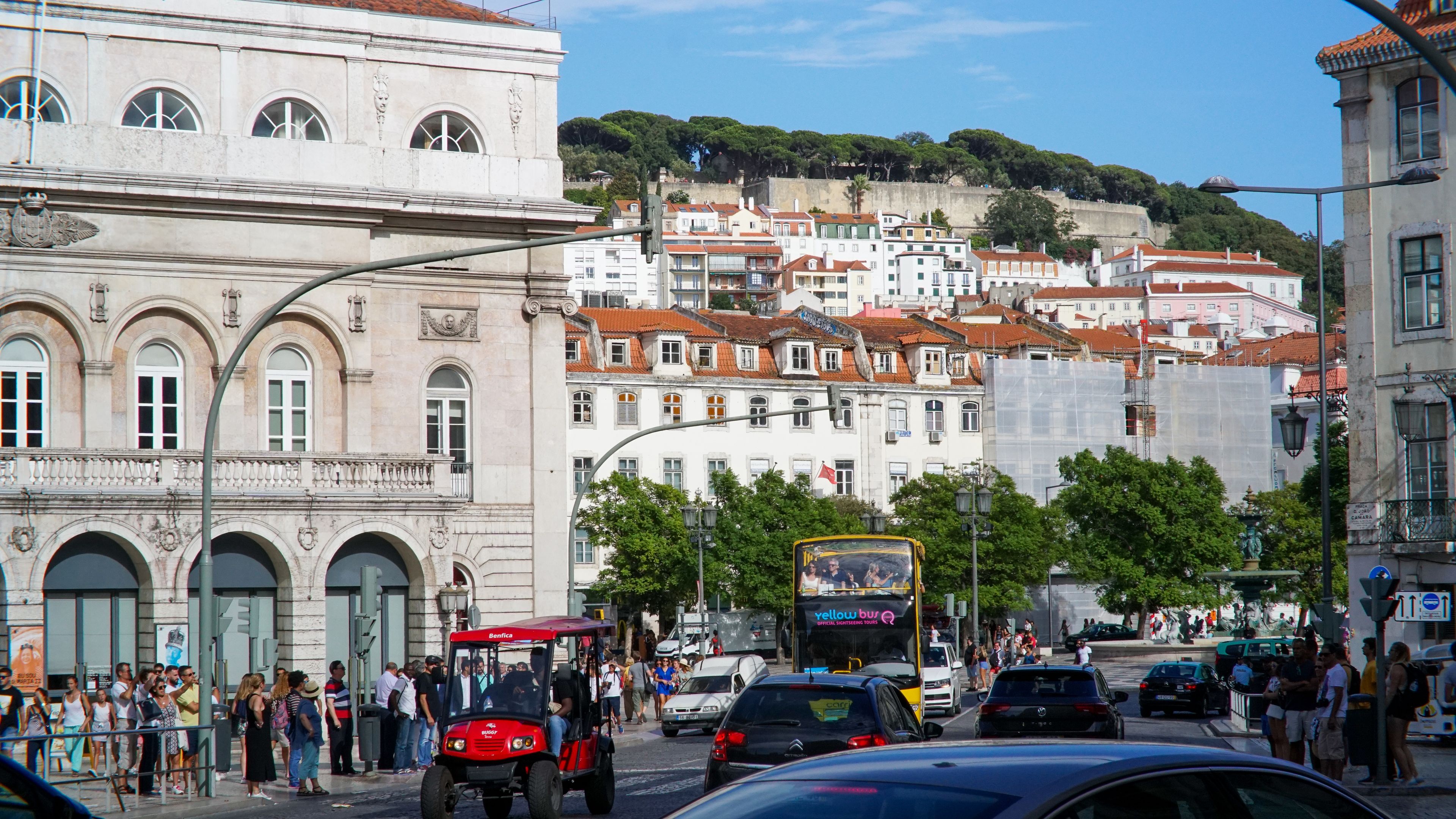 Vibrant daytime view of central Lisbon with iconic architecture and busy street life.
