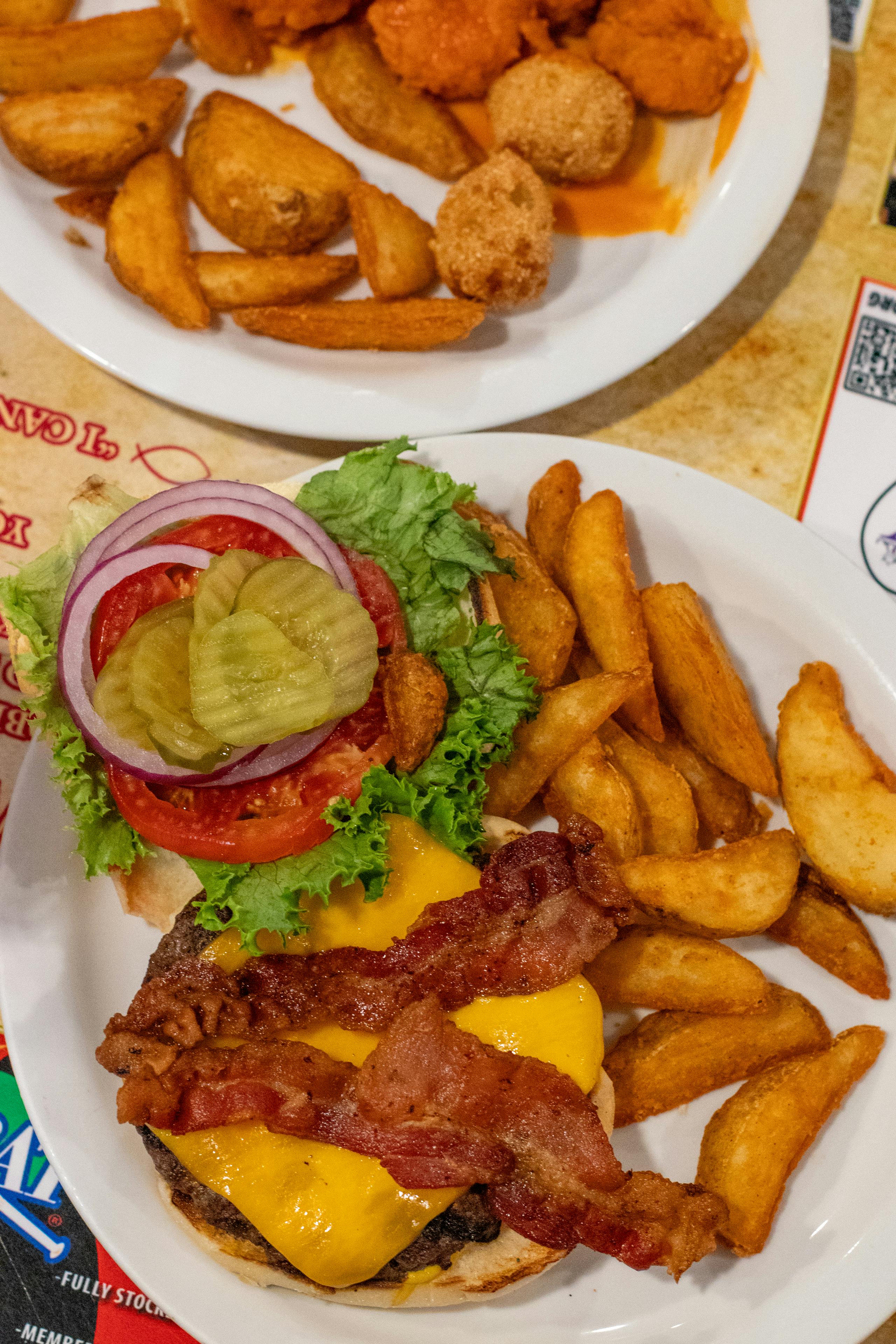 Delicious cheeseburger with bacon, lettuce, tomato, pickles, and seasoned fries served in an Alabama diner.