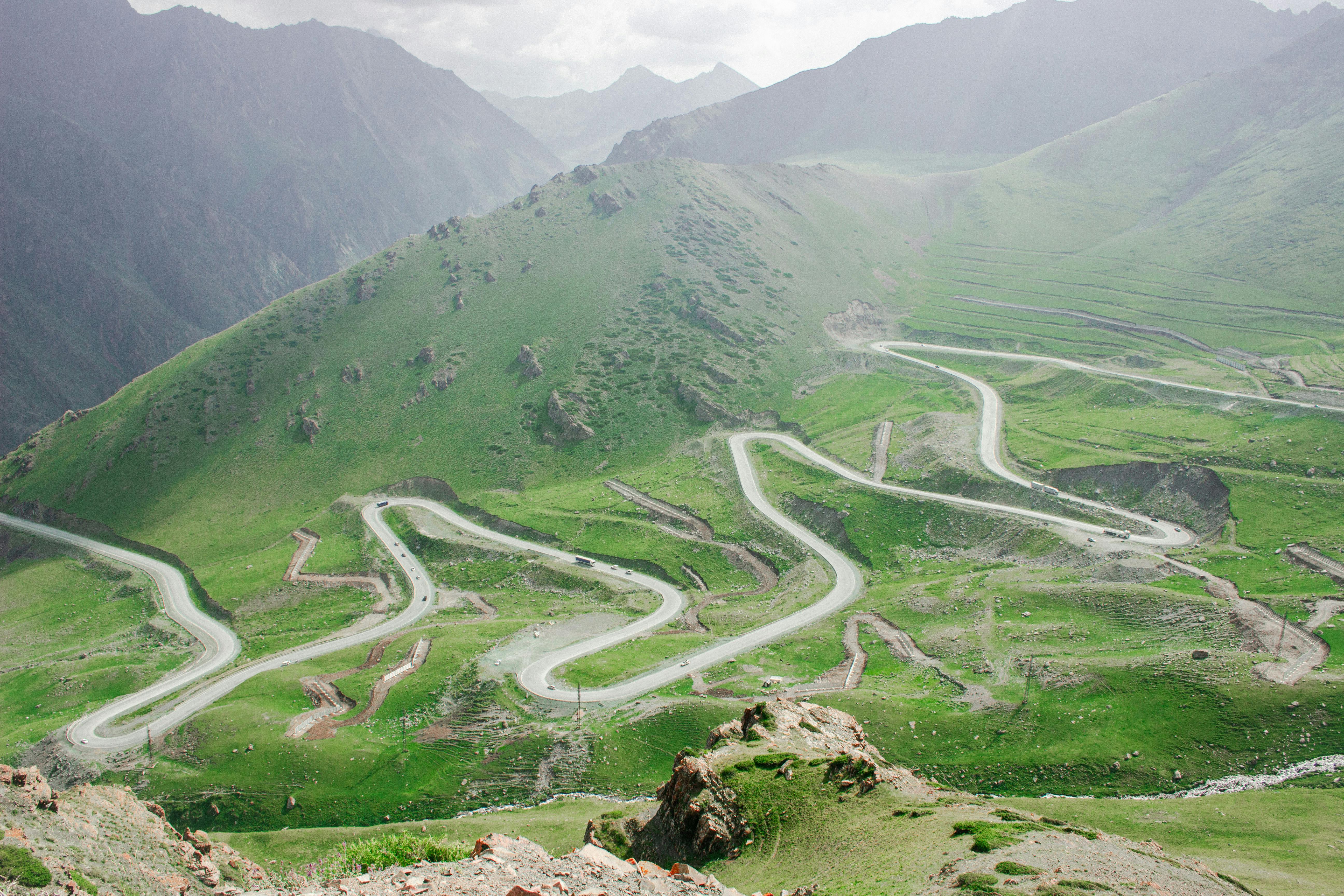 Winding mountain road through lush green hills in the Chüy Region of Kyrgyzstan.