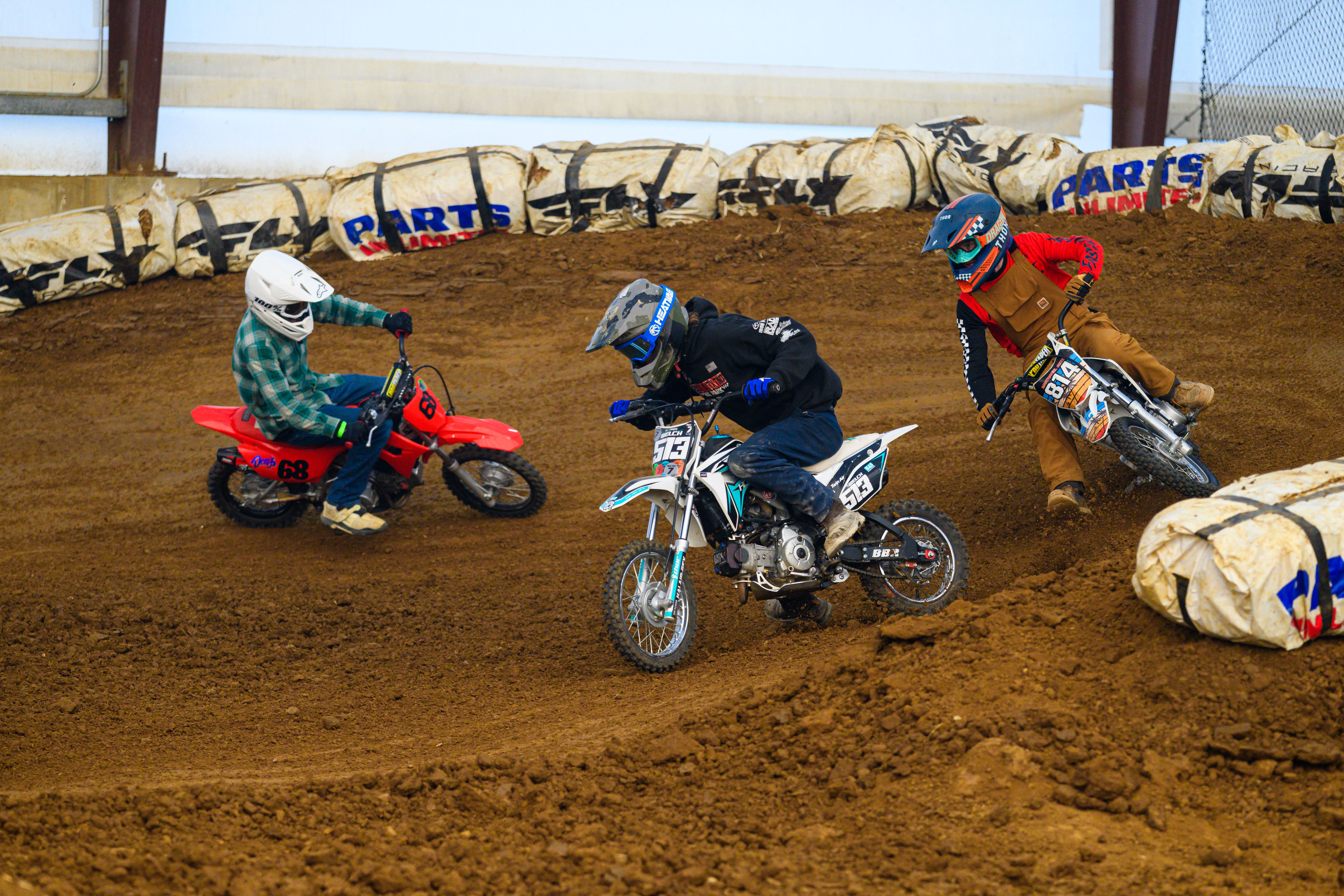 Thrilling indoor dirt bike race in Martinsburg, Ohio with young racers maneuvering tight corners.