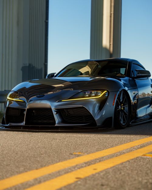 Free Shiny sports car parked on a sunlit highway under a clear blue sky. Stock Photo