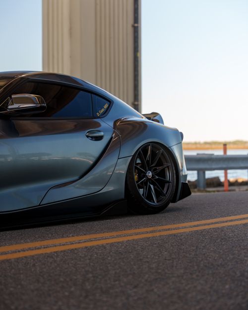 Free A modern sports car parked on a highway, showcasing its sleek design and polished finish. Stock Photo