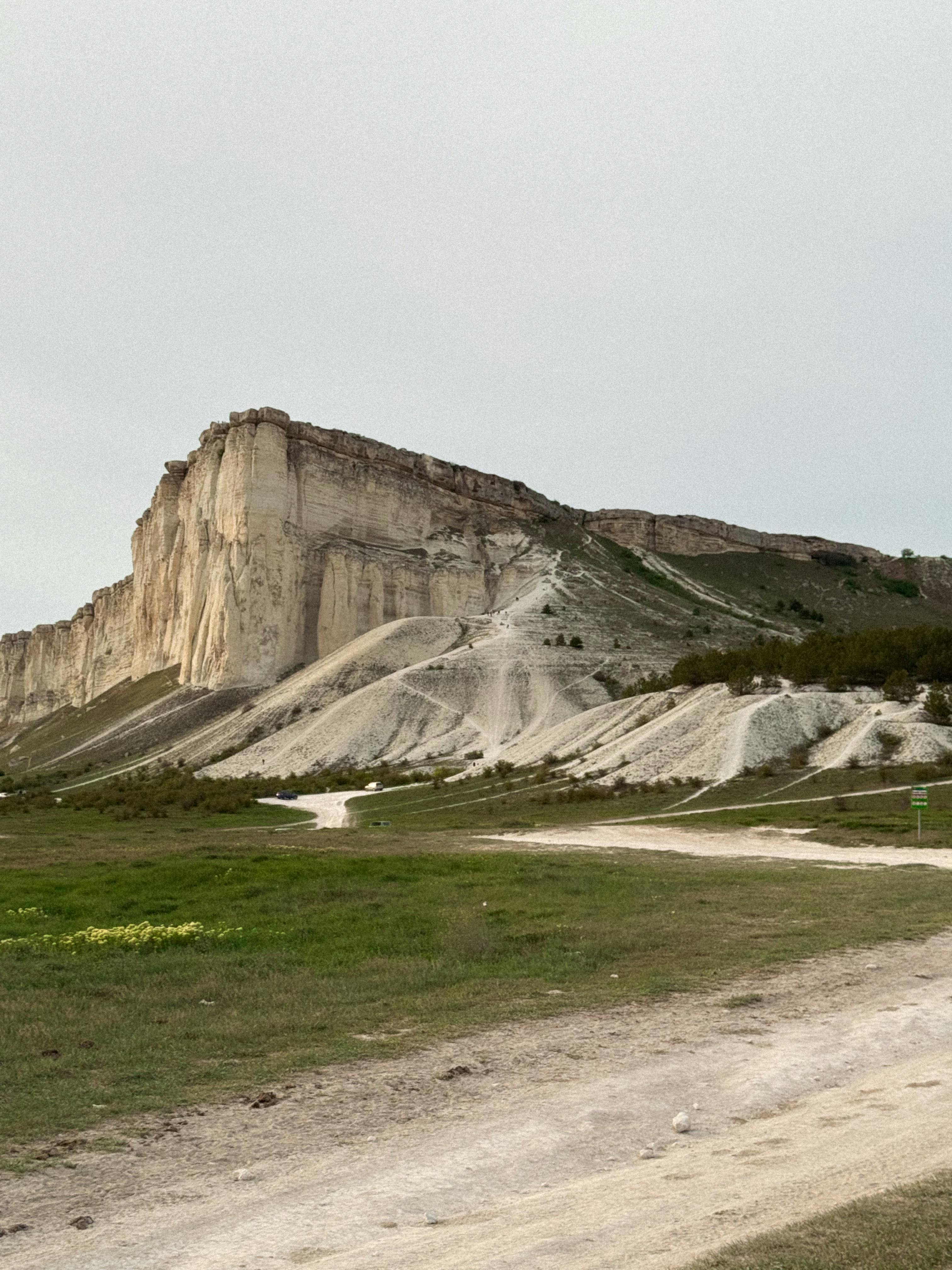 Dramatic limestone cliff with a rugged path in a scenic outdoor setting during the day.