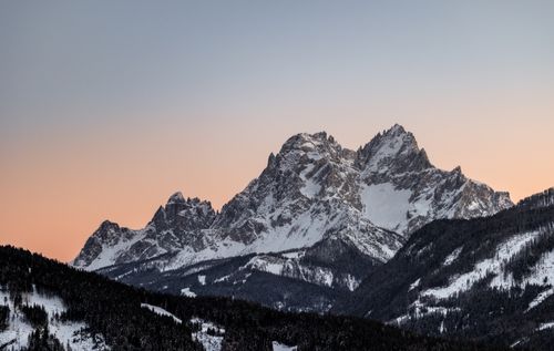 Free Stunning view of snowy mountains under a colorful sunset sky. Stock Photo