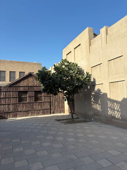 Free Beautiful blend of traditional architecture and nature in Dubai's historic district under clear skies. Stock Photo