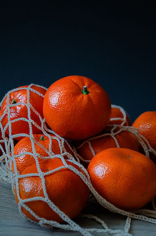 Free Vibrant mandarin oranges in a mesh bag against a dark backdrop, perfect for seasonal concepts. Stock Photo