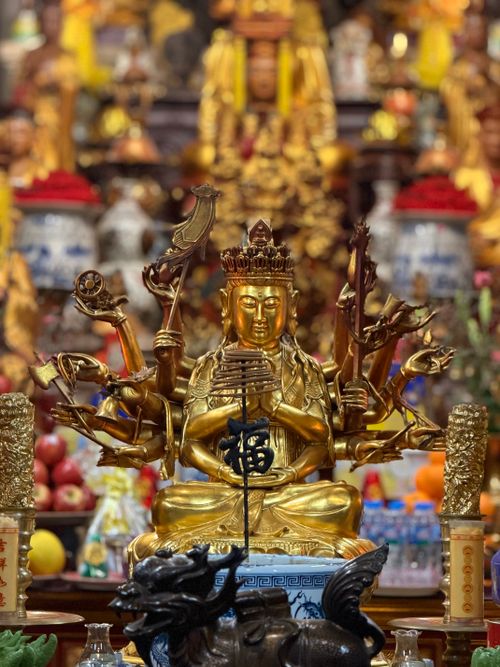 Free Intricate golden Buddhist statue with multiple arms in a richly decorated temple. Stock Photo