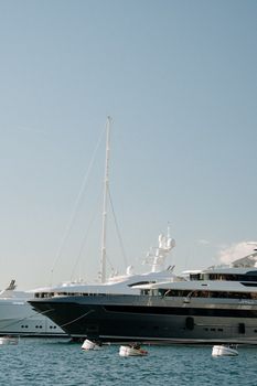 Scenic view of luxury yachts docked in the serene harbor of Perast, Montenegro under a clear sky.