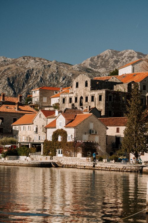 Free Picturesque coastal village with historic buildings and mountain backdrop. Stock Photo