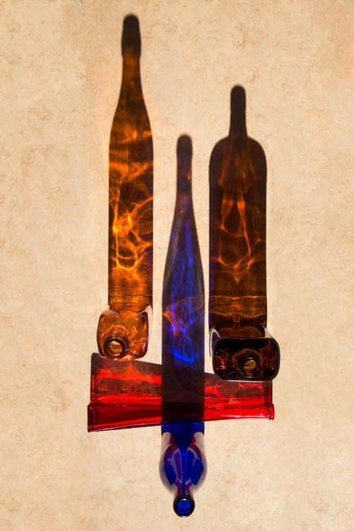Free Vibrant shadows of colored glass bottles create an abstract artistic display. Stock Photo