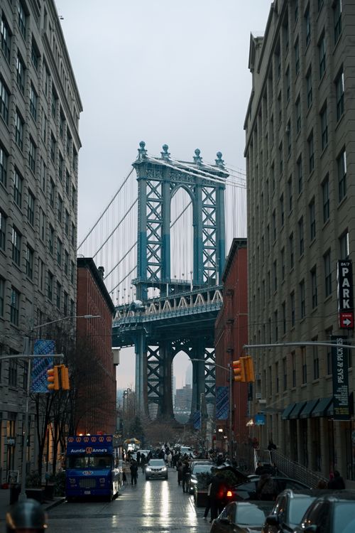 Free Street view of the Manhattan Bridge framed by Dumbo, Brooklyn buildings on an overcast day. Stock Photo