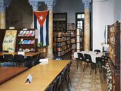 Inviting library with Cuban flag, bookshelves, and tables, ideal for study and reading.