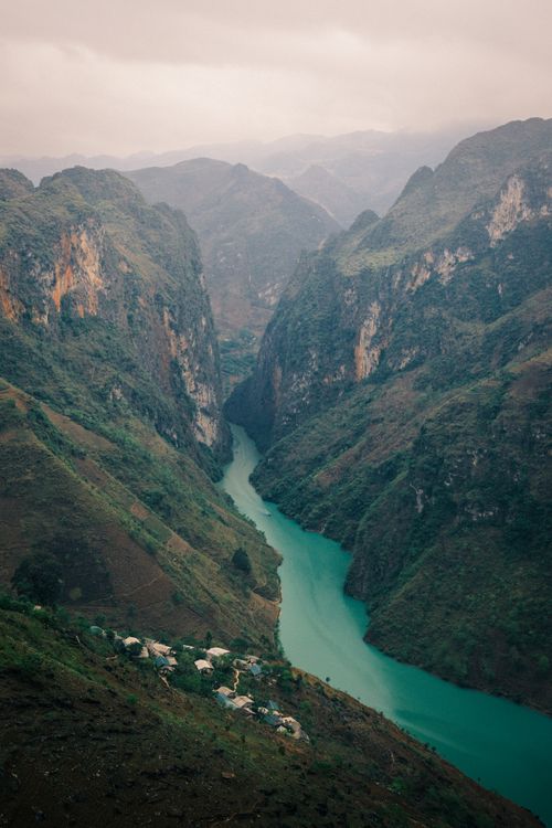 Free A breathtaking aerial view of a turquoise river winding through a lush mountain valley, showcasing nature's tranquility. Stock Photo