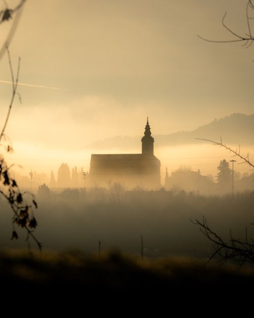 Free A church spire rises through dense fog on a misty morning, creating an ethereal landscape scene. Stock Photo