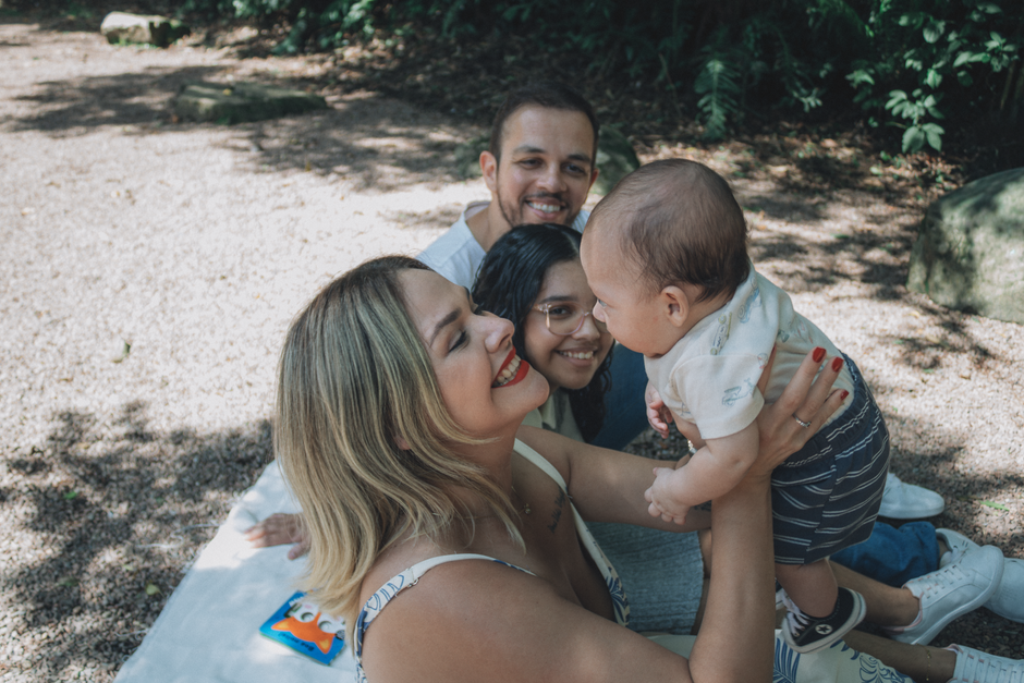 Smiling family enjoying a sunny day outdoors with their baby.