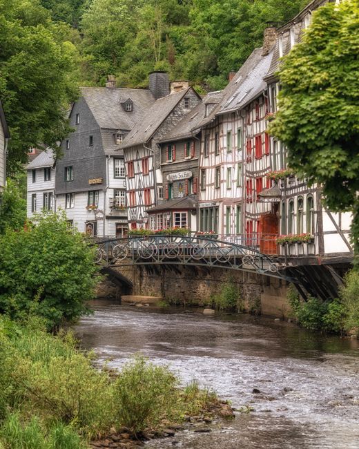 Picturesque view of traditional half-timbered houses along a scenic river in Monschau, Germany.