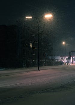 A cinematic winter scene of a quiet street in Longueuil, Quebec during snowfall at night.