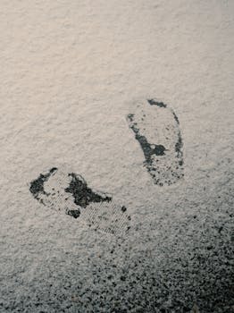 Footprints imprinted on snow-dusted street in Longueuil, Quebec, capturing a minimalist winter scene.