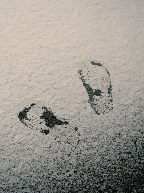 Free Footprints imprinted on snow-dusted street in Longueuil, Quebec, capturing a minimalist winter scene. Stock Photo