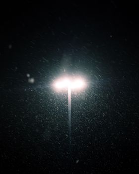 Dramatic night scene of a street lamp illuminating snowflakes in Longueuil, Quebec.