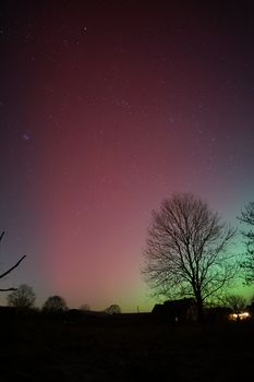 Colorful northern lights over a rural landscape in Schleswig-Holstein, Germany.