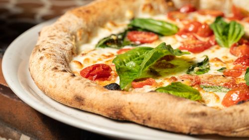 Free Delicious homemade Margarita pizza topped with fresh basil and cherry tomatoes. Stock Photo