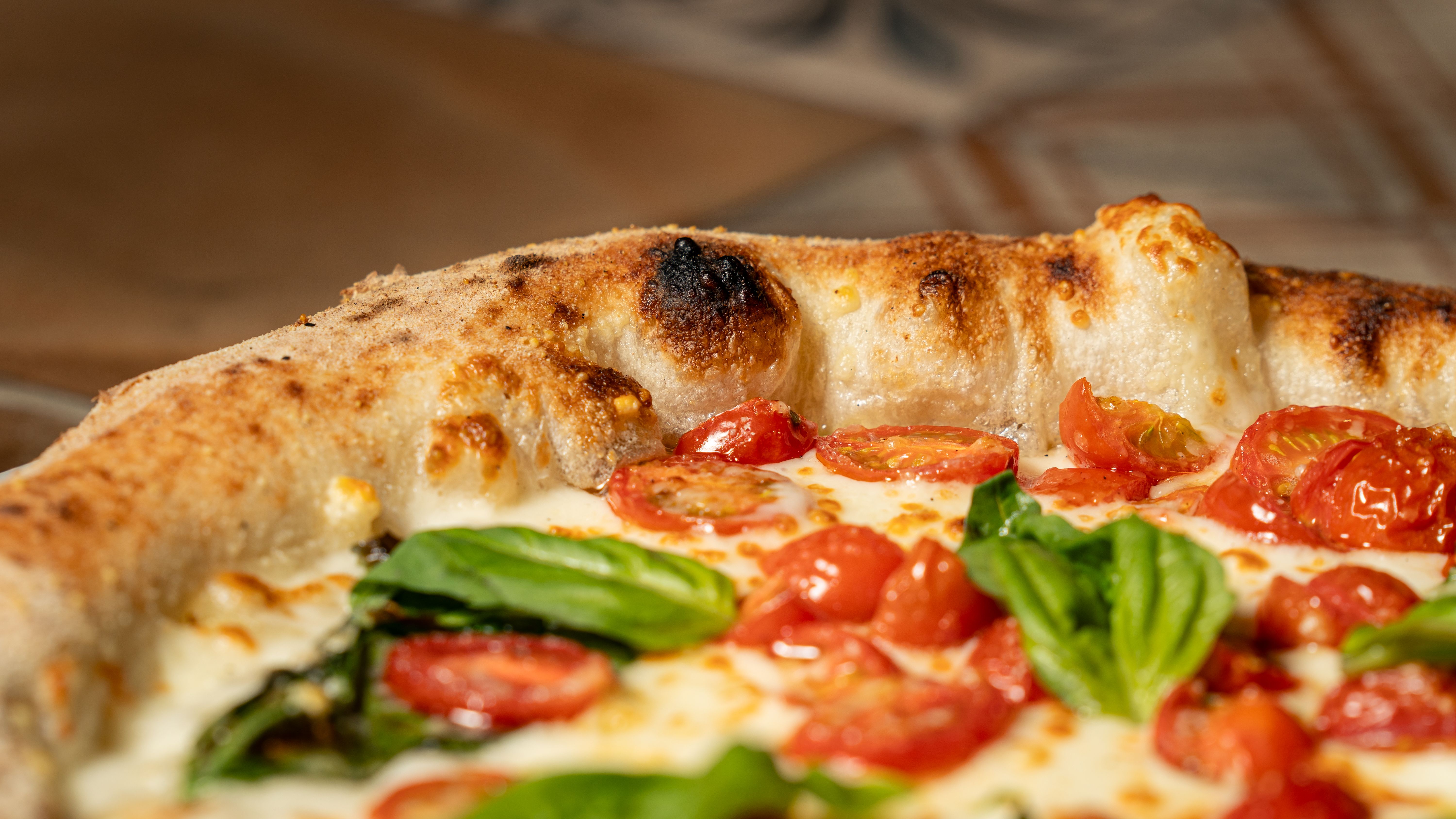 Prosciutto and arugula coal fired pizza with olive oil drizzle