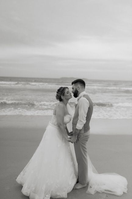 A couple shares a tender kiss on a beach during their wedding at sunset.