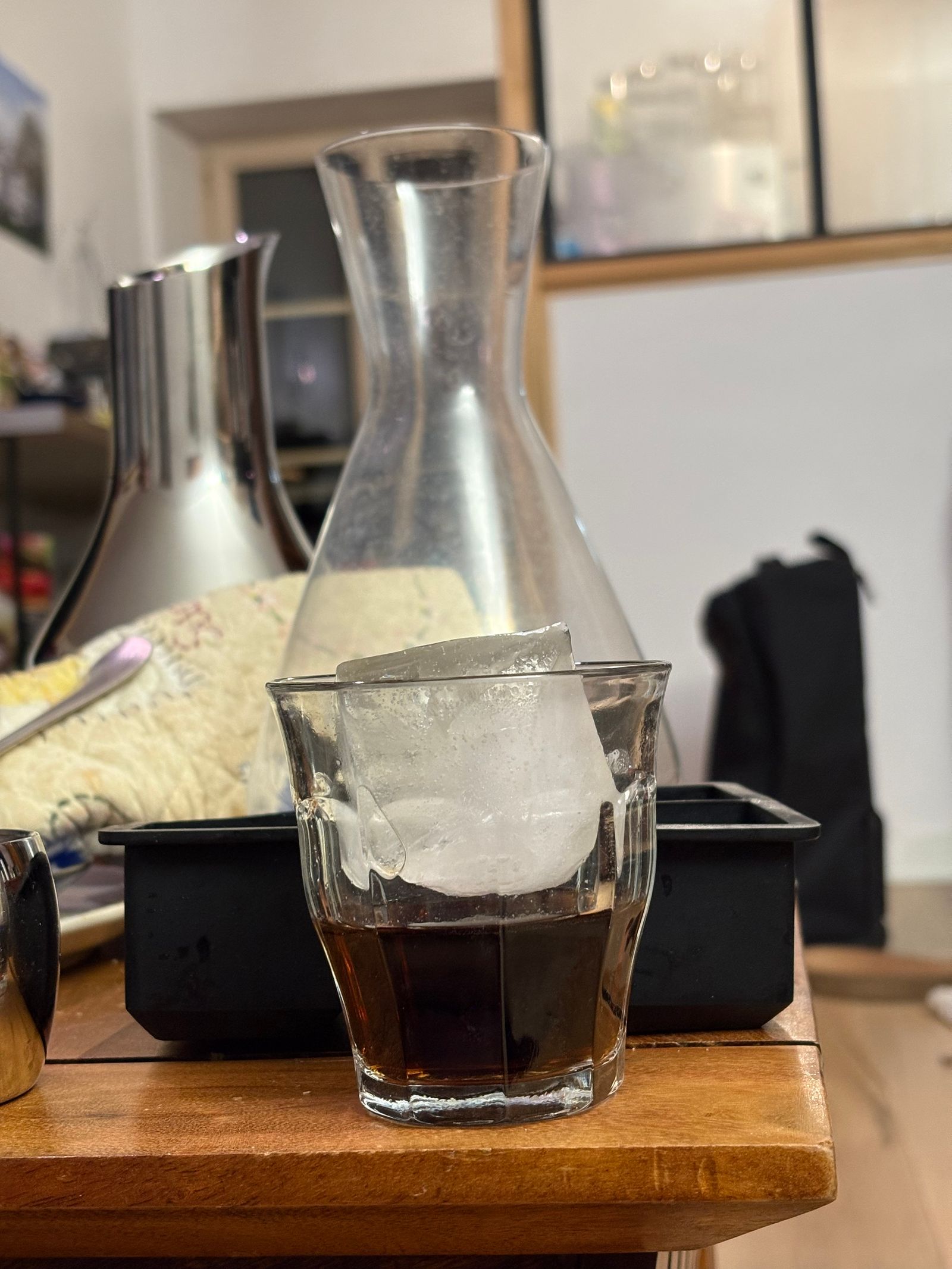 Verre de café glacé avec un gros glaçon à côté d'une carafe en verre