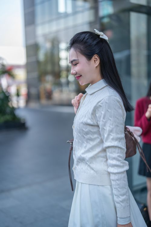 Free Side profile of a smiling young woman outdoors in an urban setting. Stock Photo