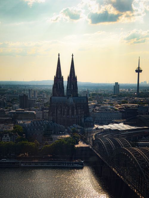 Free Aerial view of the iconic Cologne Cathedral and Rhine River during sunset with a scenic city backdrop. Stock Photo