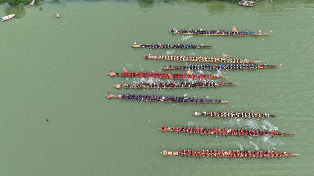A thrilling aerial view capturing a traditional dragon boat race with teams rowing in unison on a river.