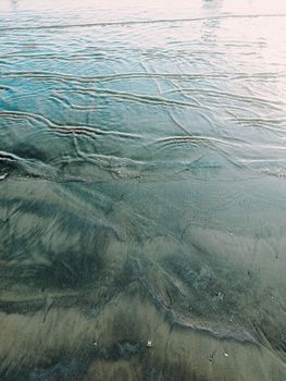 Tranquil shoreline displaying rippling water and sand patterns in Sindh, Pakistan.