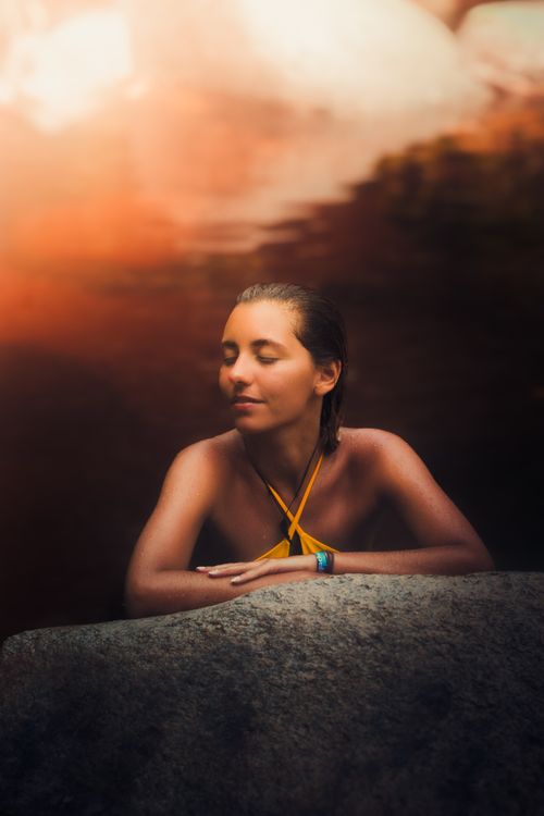 Free A woman relaxes at a river with eyes closed, embracing nature's tranquility in a swimsuit. Stock Photo