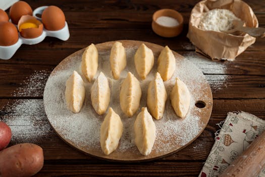Freshly prepared traditional pierogis on a floured board ready for cooking.