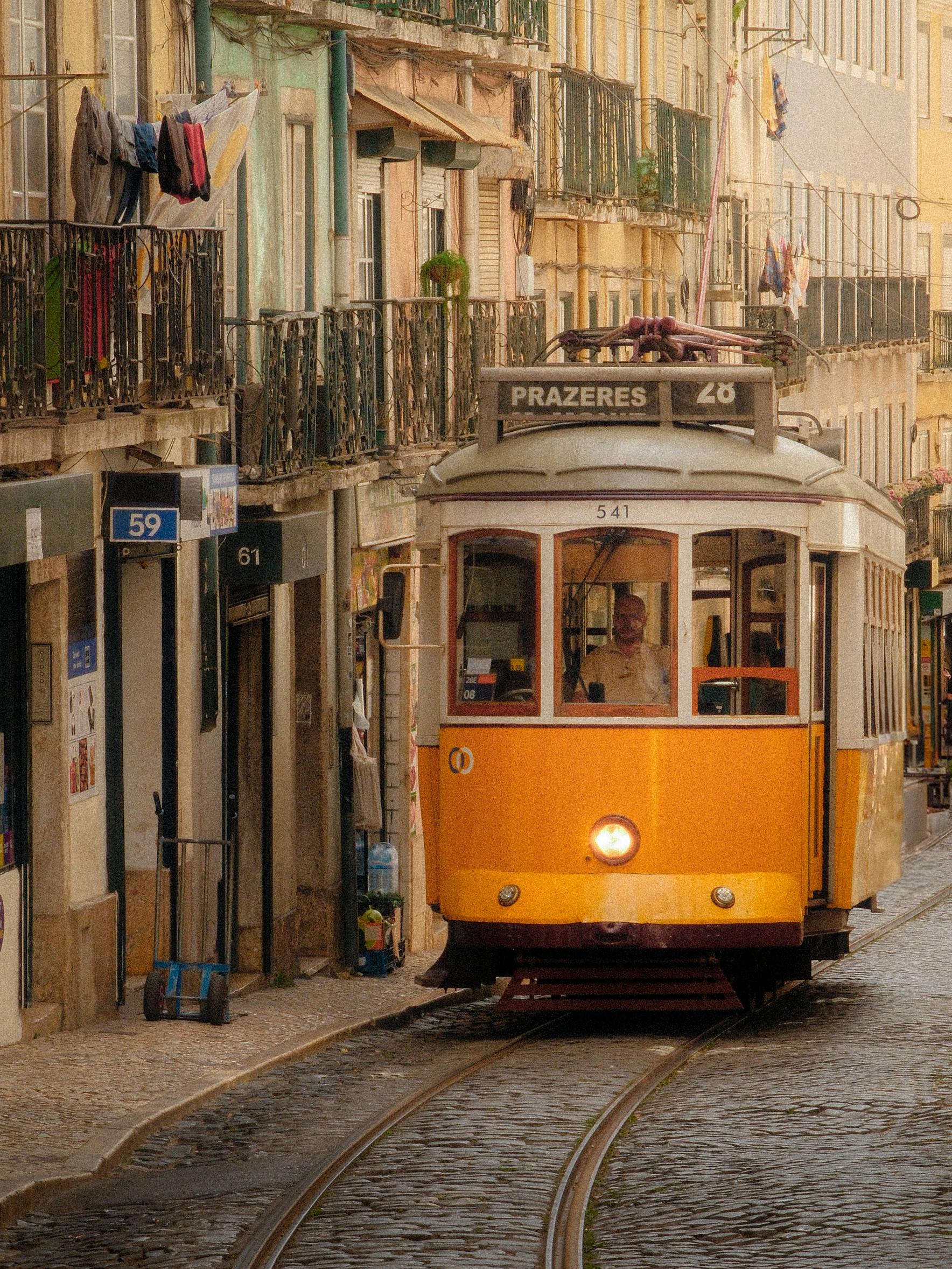 Classic yellow tram in Lisbon navigating cobbled streets, capturing vintage urban charm.