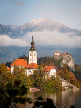Beautiful landscape of Bled Island Church with stunning mountains and autumn colors, Slovenia.