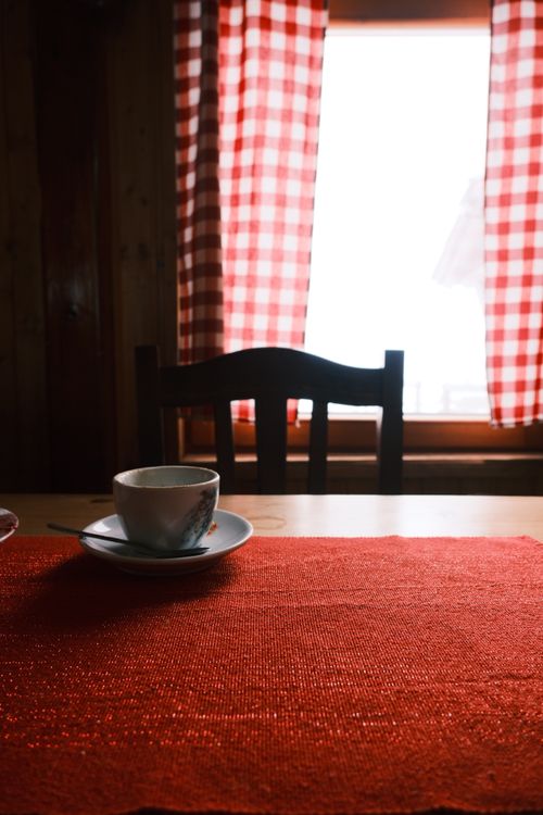 Free Warm rustic interior with a coffee cup on a table and checkered curtains. Stock Photo