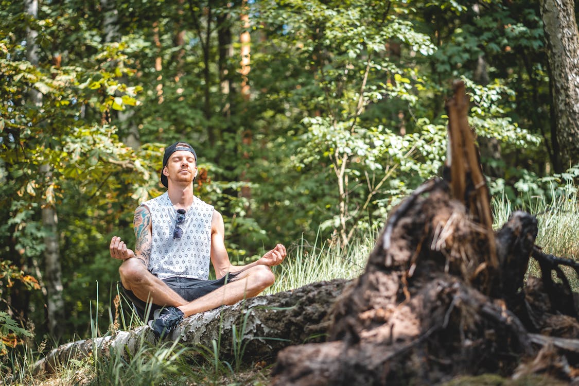 Free Man Meditating on a Tree Log Stock Photo