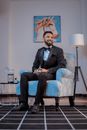 Man in Black Suit Sitting on Blue Floral Armchair