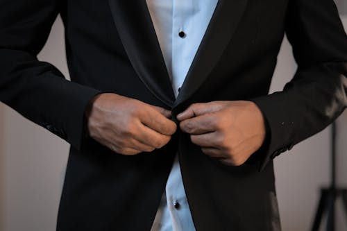 Businessman buttoning up blazer of elegant suit